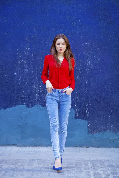 Giovane bella ragazza in jeans blu e una camicia rossa sul retro — Foto Stock