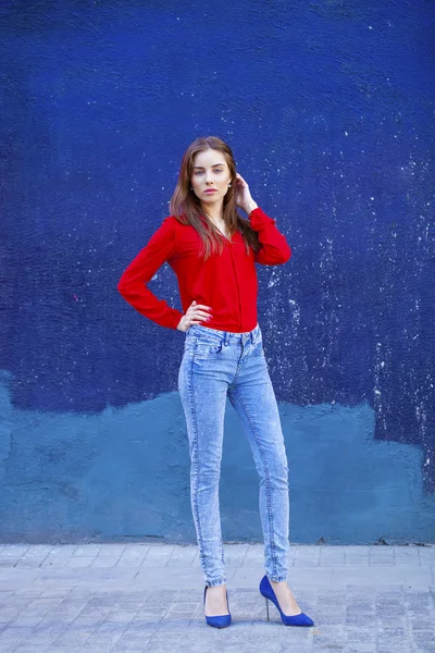 Krásná mladá dívka v džínách a červené tričko na pozadí, vyřešit hádank — Stock fotografie