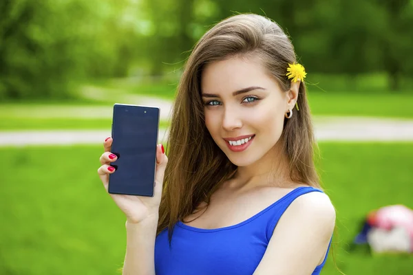 Junge schöne brünette Frau zeigt ein neues Smartphone — Stockfoto