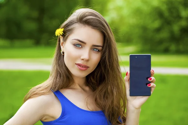 Όμορφη μελαχρινή νεαρή γυναίκα δείχνει ένα νέο έξυπνο τηλέφωνο — Φωτογραφία Αρχείου