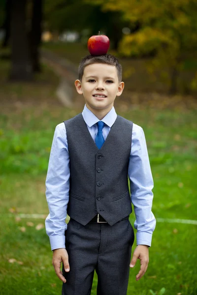 Ein kleiner Junge hält einen roten Apfel auf dem Hintergrund des Herbstparks — Stockfoto