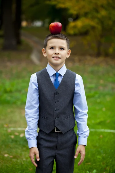 Ein kleiner Junge hält einen roten Apfel auf dem Hintergrund des Herbstparks — Stockfoto