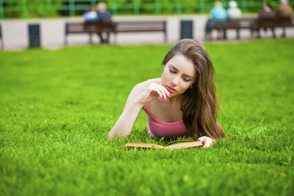 Jeune belle fille brune lisant un livre en plein air — Photo