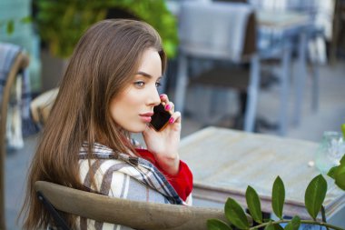 Genç güzel kız yaz kafe ve telefon ederken oturuyor