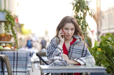 Genç güzel kız yaz kafe ve telefon ederken oturuyor