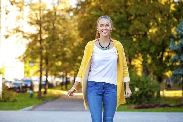 Glad ung kvinna i gul jacka på hösten gatan — Stockfoto