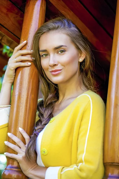 Happy young woman standing on the porch of a wooden house — Stock Photo, Image