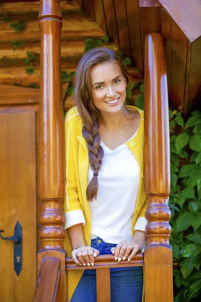 Giovane donna felice in piedi sul portico di una casa di legno — Foto Stock
