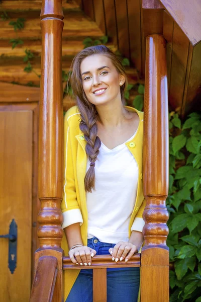 Щаслива молода жінка стоїть на ганку дерев'яного будинку — стокове фото