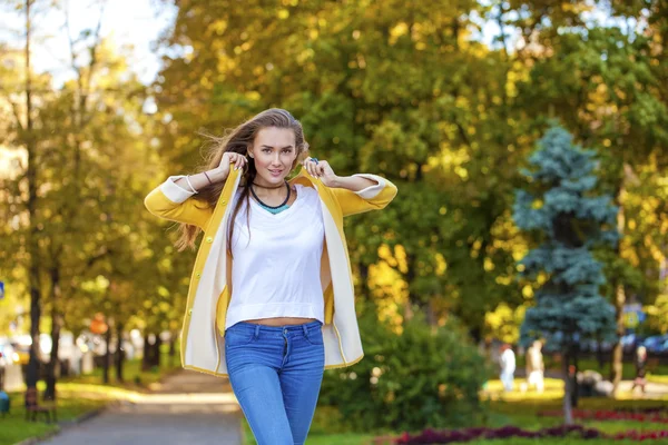 Szczęśliwa młoda kobieta w żółty płaszcz jesień ulicy — Zdjęcie stockowe