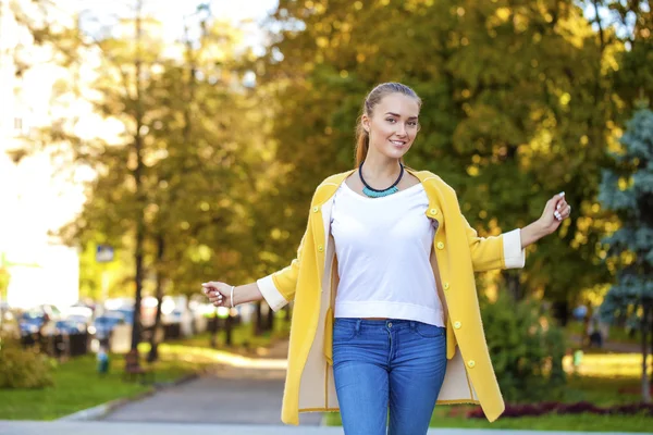 Mujer joven feliz en abrigo amarillo en la calle de otoño — Foto de Stock