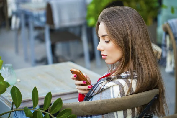 Young beautiful girl sits in summer cafe and calling by phone — Stock Photo, Image