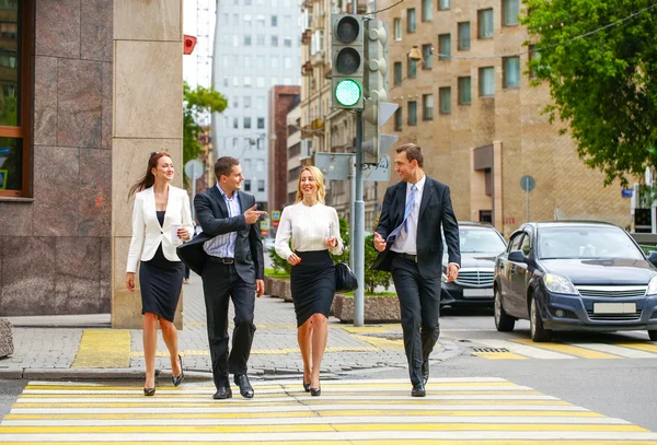 Vier succesvolle zakenmensen oversteken van de straat in de stad — Stockfoto