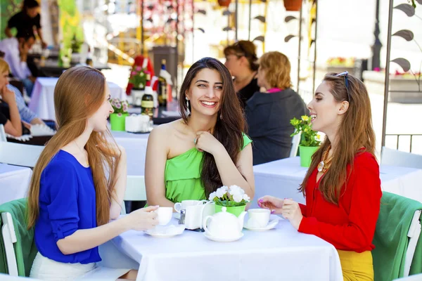Три счастливые подруги женщины, сидящие за столом летом c — стоковое фото
