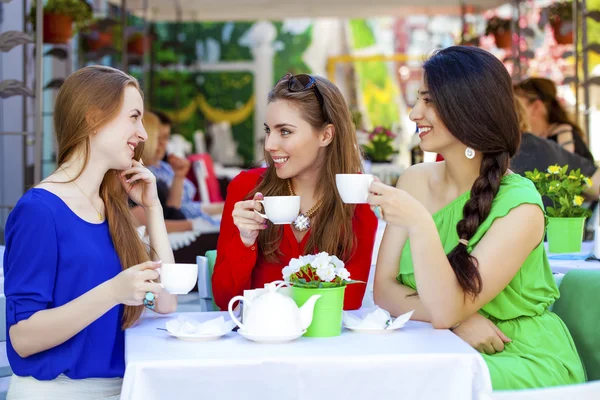 Drie gelukkige vriendinnen vrouw zitten aan een tafel in de zomer c — Stockfoto