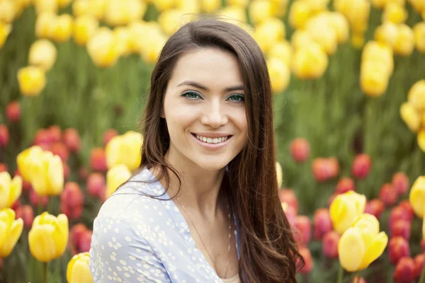 Schöne junge Frau auf dem Hintergrund von Tulpen — Stockfoto