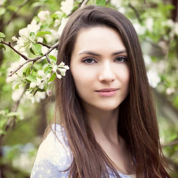 Mulher bonita de pé perto de árvores florescendo no jardim de primavera — Fotografia de Stock