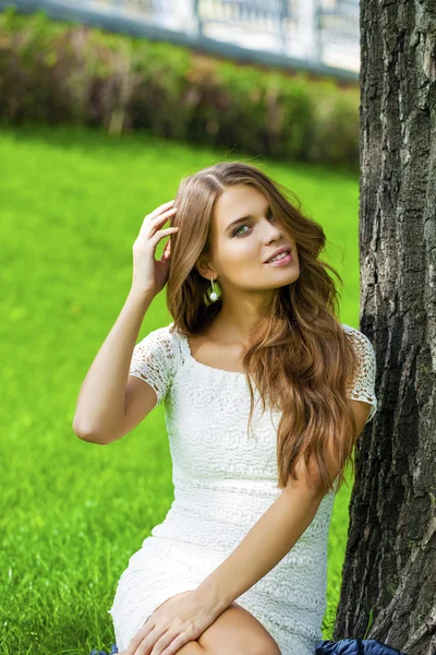 年轻漂亮的女孩坐在绿色的草地上 — 图库照片