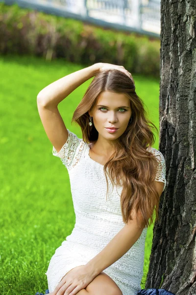 年轻漂亮的女孩坐在绿色的草地上 — 图库照片