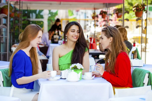 Drie gelukkige vriendinnen vrouw zitten aan een tafel in de zomer c — Stockfoto
