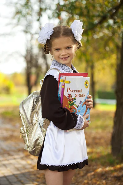 Happy little schoolgirl in autumn park — Stock Photo, Image
