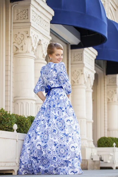 Hermosa chica rubia en vestido azul posando sobre un fondo — Foto de Stock