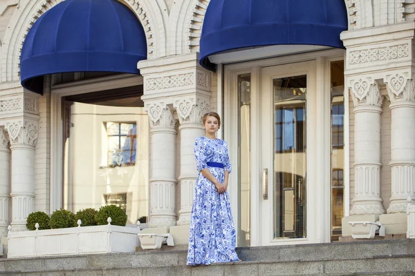 Bella ragazza bionda in abito blu posa su uno sfondo — Foto Stock