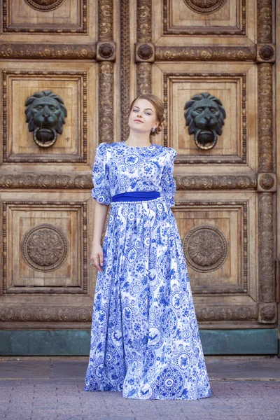 Hermosa chica rubia en vestido azul posando sobre un fondo — Foto de Stock
