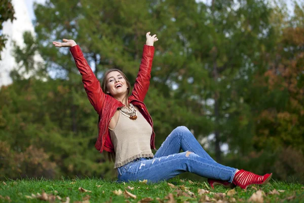 Hppy beautiful woman in red leather jacket and blue jeans sittin — Stock Photo, Image
