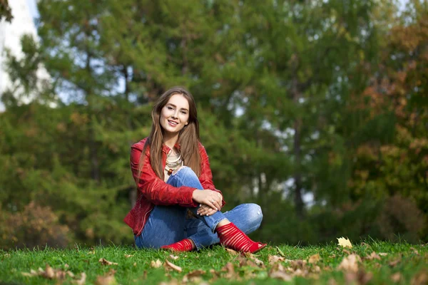 De mooie vrouw hppy in rood lederen jas en blue jeans sittin — Stockfoto