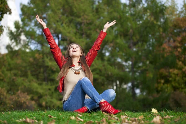 De mooie vrouw hppy in rood lederen jas en blue jeans sittin — Stockfoto