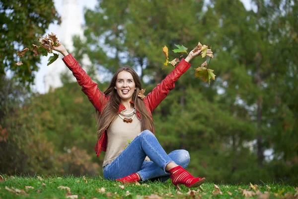 Hppy beautiful woman in red leather jacket and blue jeans sittin — Stock Photo, Image