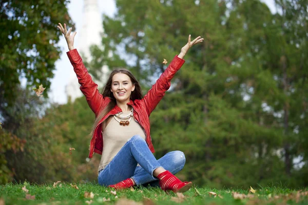 Hppy schöne Frau in roter Lederjacke und blauer Jeans sittin — Stockfoto