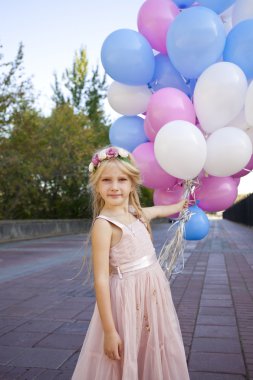 Balonlar tutan pembe elbiseli küçük beş yıllık kız