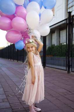Balonlar tutan pembe elbiseli küçük beş yıllık kız