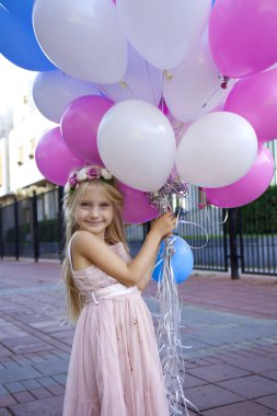 Balonlar tutan pembe elbiseli küçük beş yıllık kız