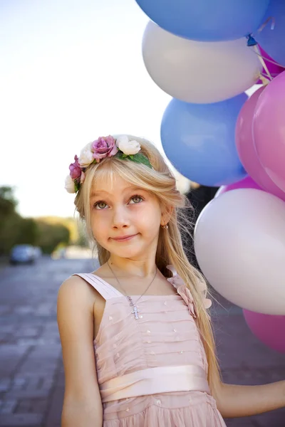 Niña de cinco años con un vestido rosa sosteniendo globos — Foto de Stock