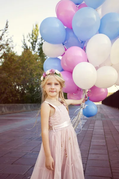 Pequena menina de cinco anos em um vestido rosa segurando balões — Fotografia de Stock