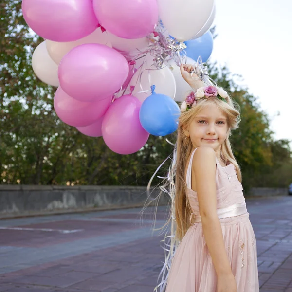 Pequena menina de cinco anos em um vestido rosa segurando balões — Fotografia de Stock