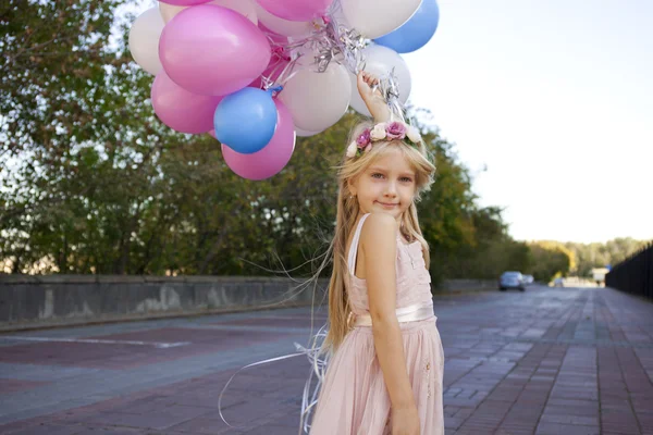 Маленька п'ятирічна дівчинка в рожевій сукні тримає повітряні кулі — стокове фото