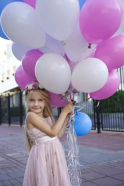 Niña de cinco años con un vestido rosa sosteniendo globos — Foto de Stock