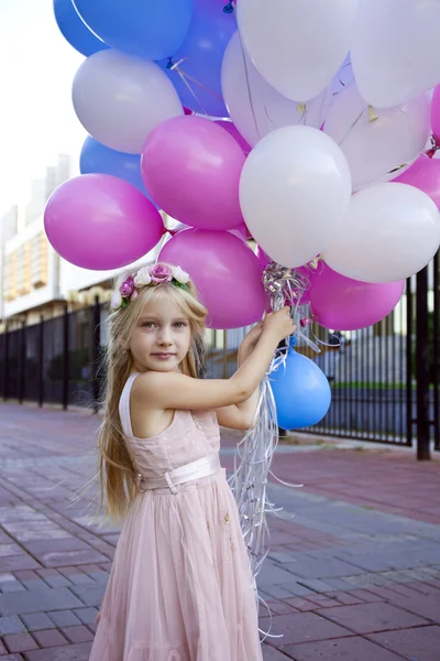 Niña de cinco años con un vestido rosa sosteniendo globos — Foto de Stock