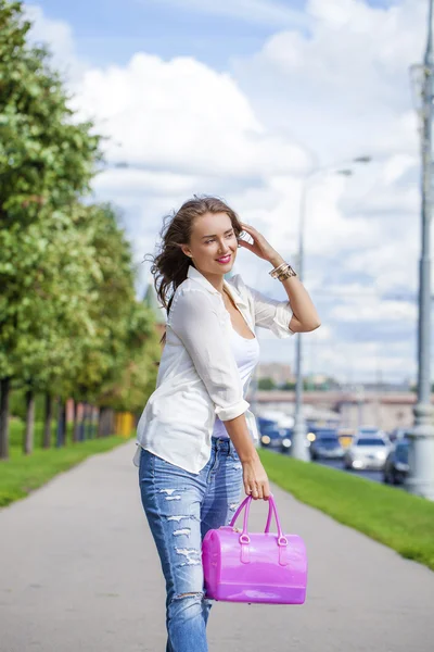 Young beautiful woman in white blouse and blue jeans walking in Royalty Free Stock Images