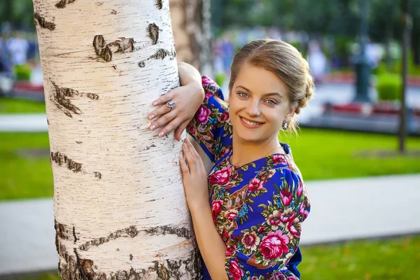 Mulher loira bonita em uma árvore em uma floresta — Fotografia de Stock