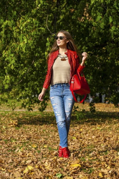 Jonge vrouw in mode rode jas en rode zak wandelen in de herfst — Stockfoto