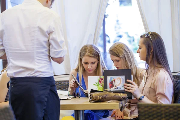 Grupo de mujeres jóvenes sentadas alrededor de la mesa comiendo postre —  Fotos de Stock