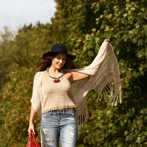 Mujer joven en jeans azules de moda y bolso rojo caminando en otoño —  Fotos de Stock