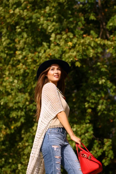 Jovem mulher na moda jeans azul e saco vermelho andando no outono — Fotografia de Stock