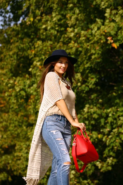 Giovane donna in jeans blu moda e borsa rossa a piedi in autunno — Foto Stock