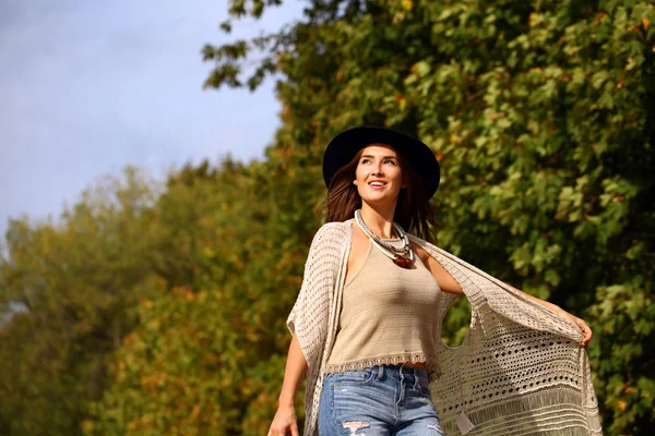 Wanita muda dengan celana jeans biru dan tas merah berjalan di musim gugur — Stok Foto